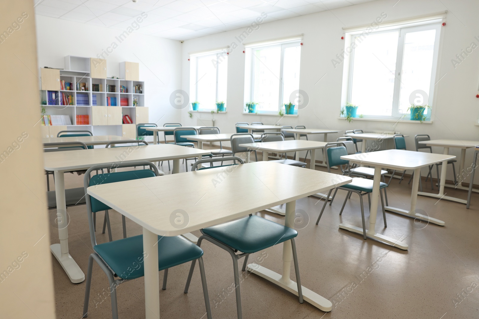 Photo of Empty school classroom with desks, windows and chairs