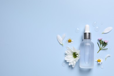 Bottle of cosmetic serum, flowers and petals on light blue background, flat lay. Space for text