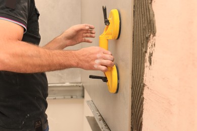 Worker using suction plate for tile installation indoors, closeup
