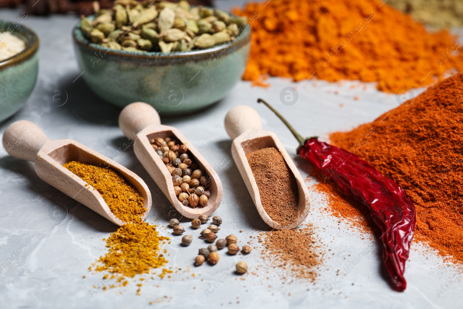 Photo of Scoops with different spices on gray marble table, closeup