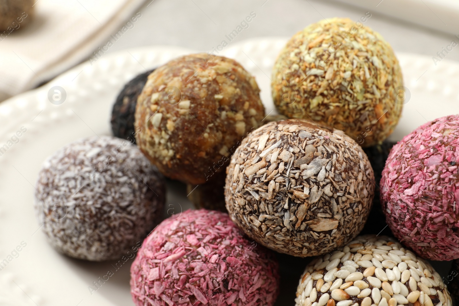 Photo of Different delicious vegan candy balls on plate, closeup
