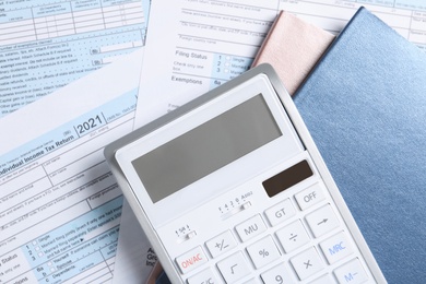 Photo of Calculator and notebooks on documents, flat lay. Tax accounting