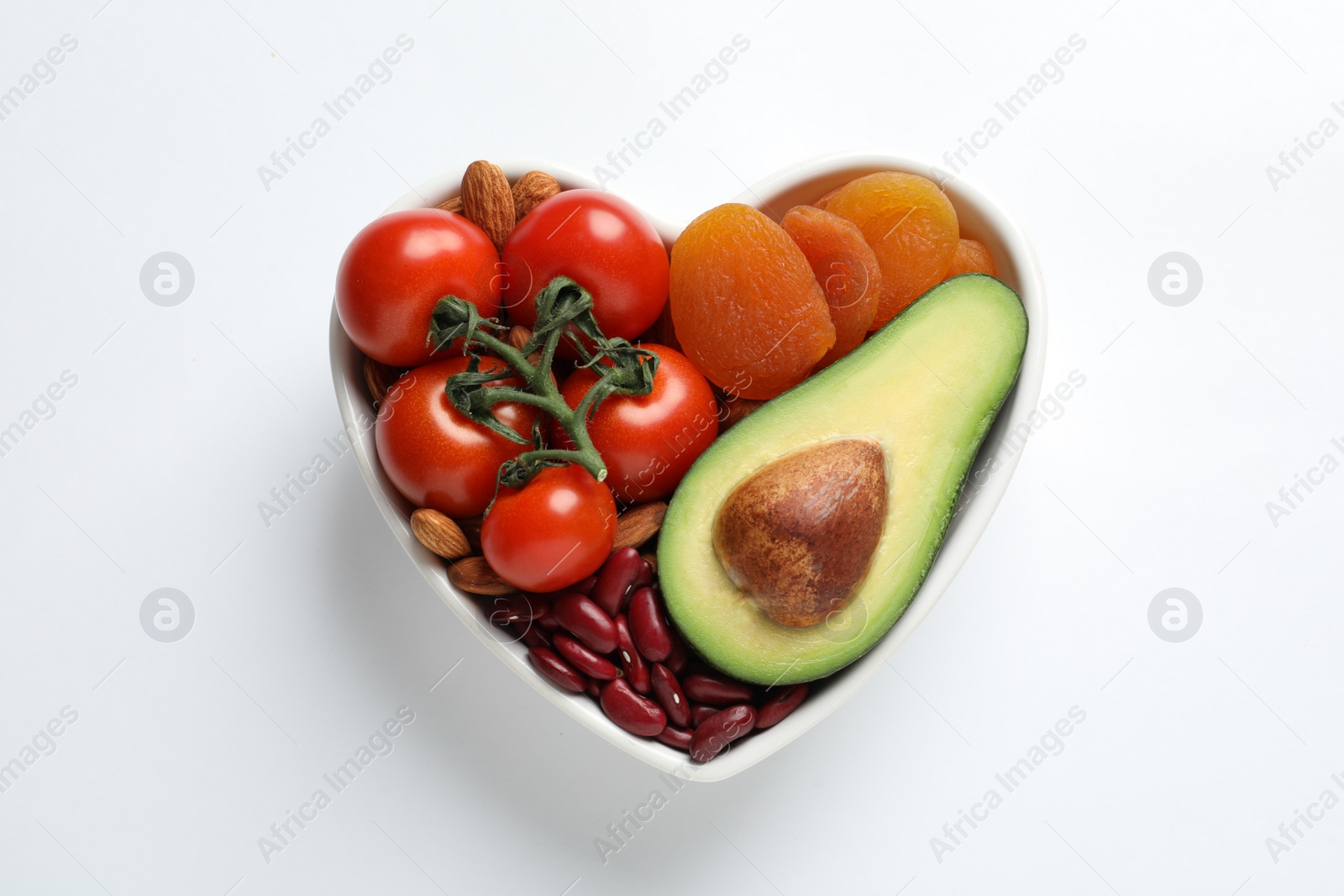 Photo of Heart shaped bowl with healthy products on white background, top view