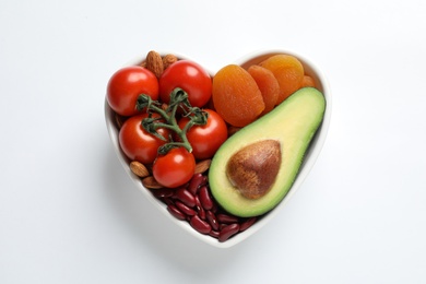 Heart shaped bowl with healthy products on white background, top view