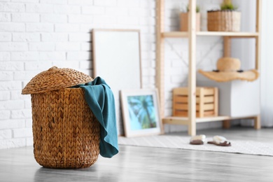 Photo of Wicker basket with blanket in modern room interior. Space for text