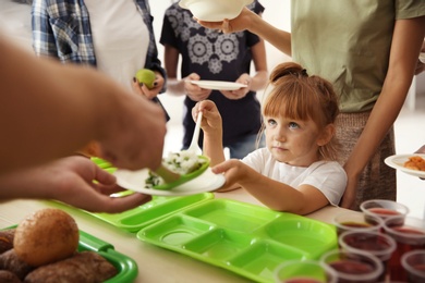 Volunteers serving food for poor people indoors