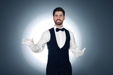 Happy professional conductor with baton on grey background