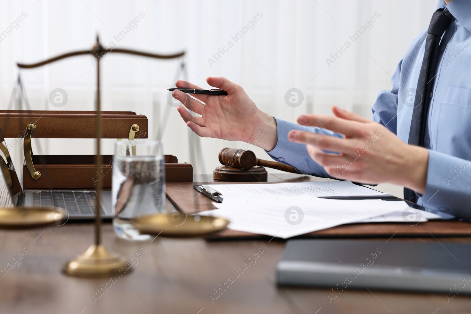 Photo of Lawyer with pen working at wooden table, closeup