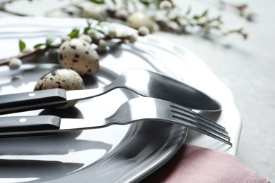 Festive Easter table setting with quail eggs on color background, closeup