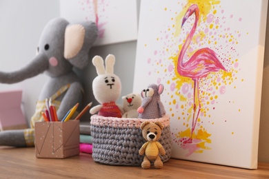 Photo of Stationery, picture and toys on wooden table in children's room. Interior design