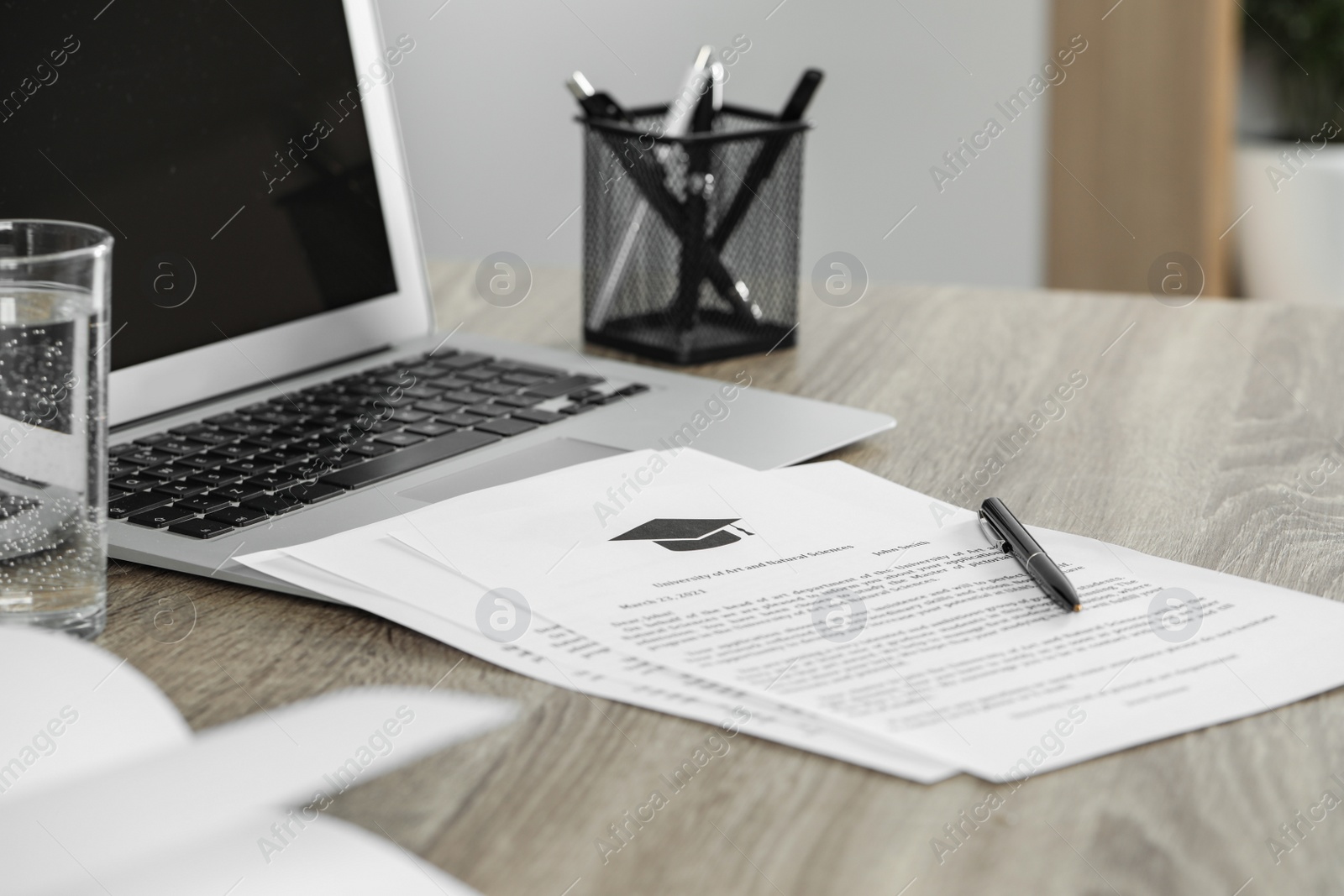 Photo of Acceptance letters from universities and laptop on wooden table indoors, closeup