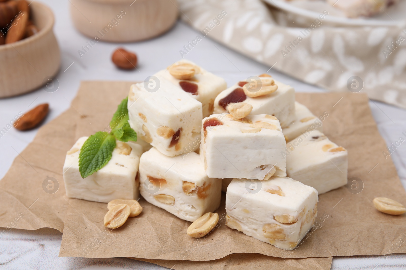 Photo of Pieces of delicious nutty nougat on parchment paper, closeup