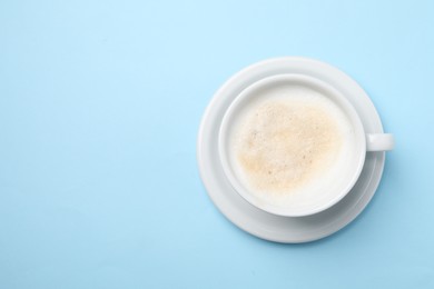 Photo of Aromatic coffee in cup on light blue background, top view. Space for text