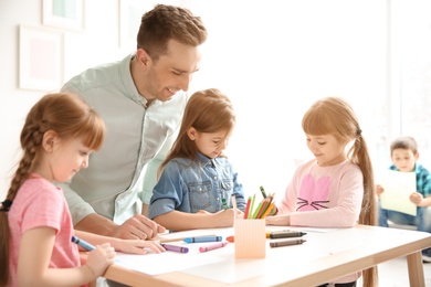 Photo of Cute little children with teacher in classroom at school