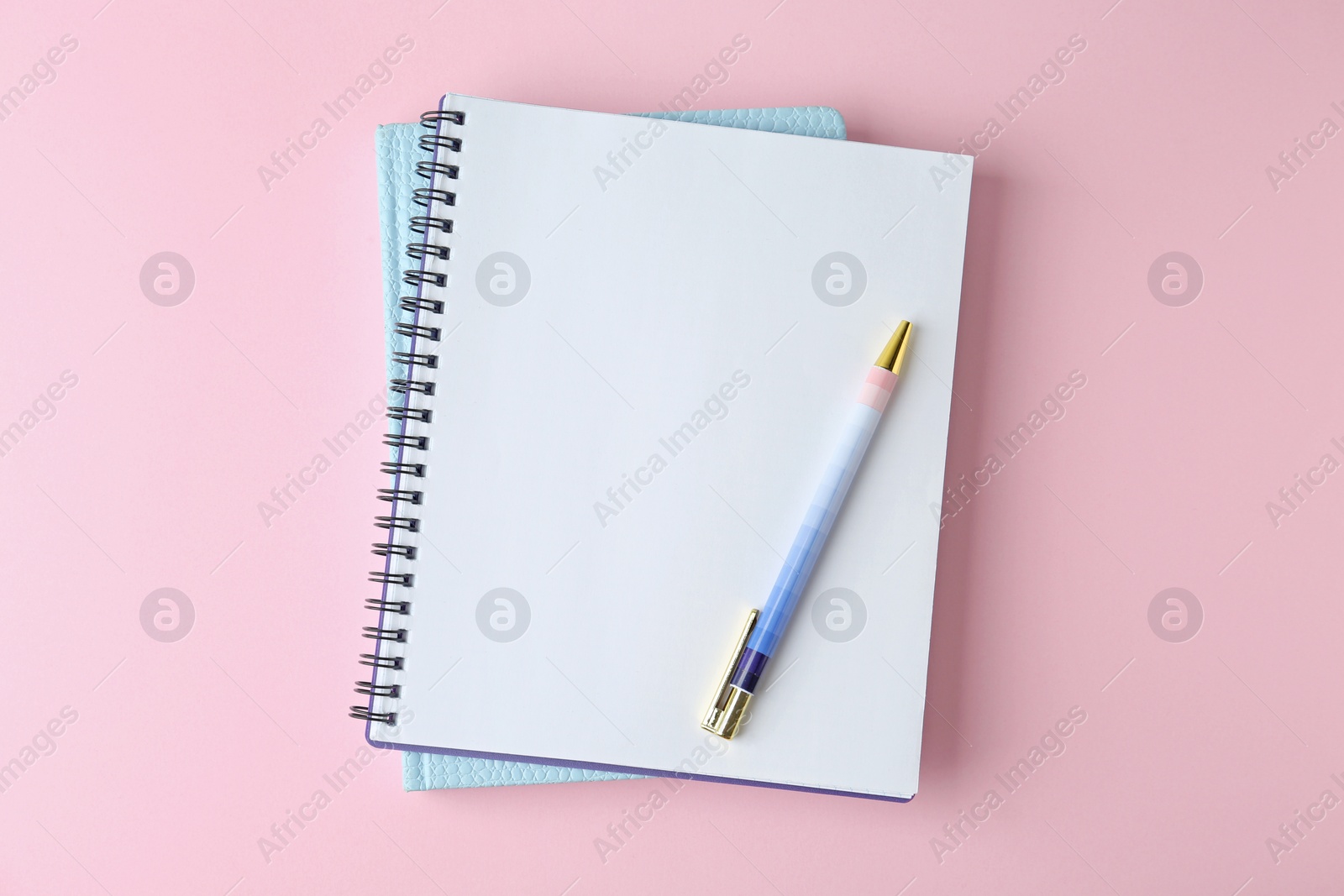 Photo of Notebooks and pen on pink background, top view