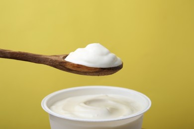 Eating delicious natural yogurt on yellow background