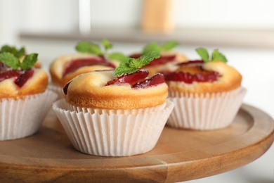 Photo of Delicious cupcakes with plums on wooden tray, closeup