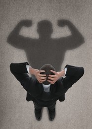 Image of Businessman and shadow of strong muscular man on floor in front of him. Concept of inner strength