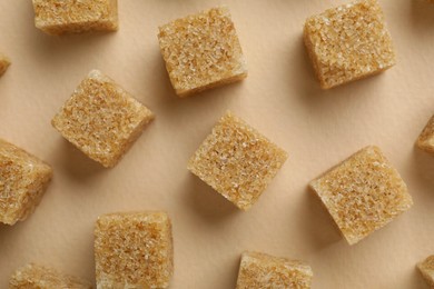 Photo of Brown sugar cubes on beige background, top view