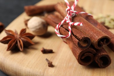 Photo of Cinnamon sticks and other spices on wooden board, closeup