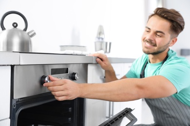 Young man baking something in oven at home