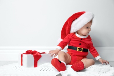 Photo of Cute little baby in Christmas costume with gift at home