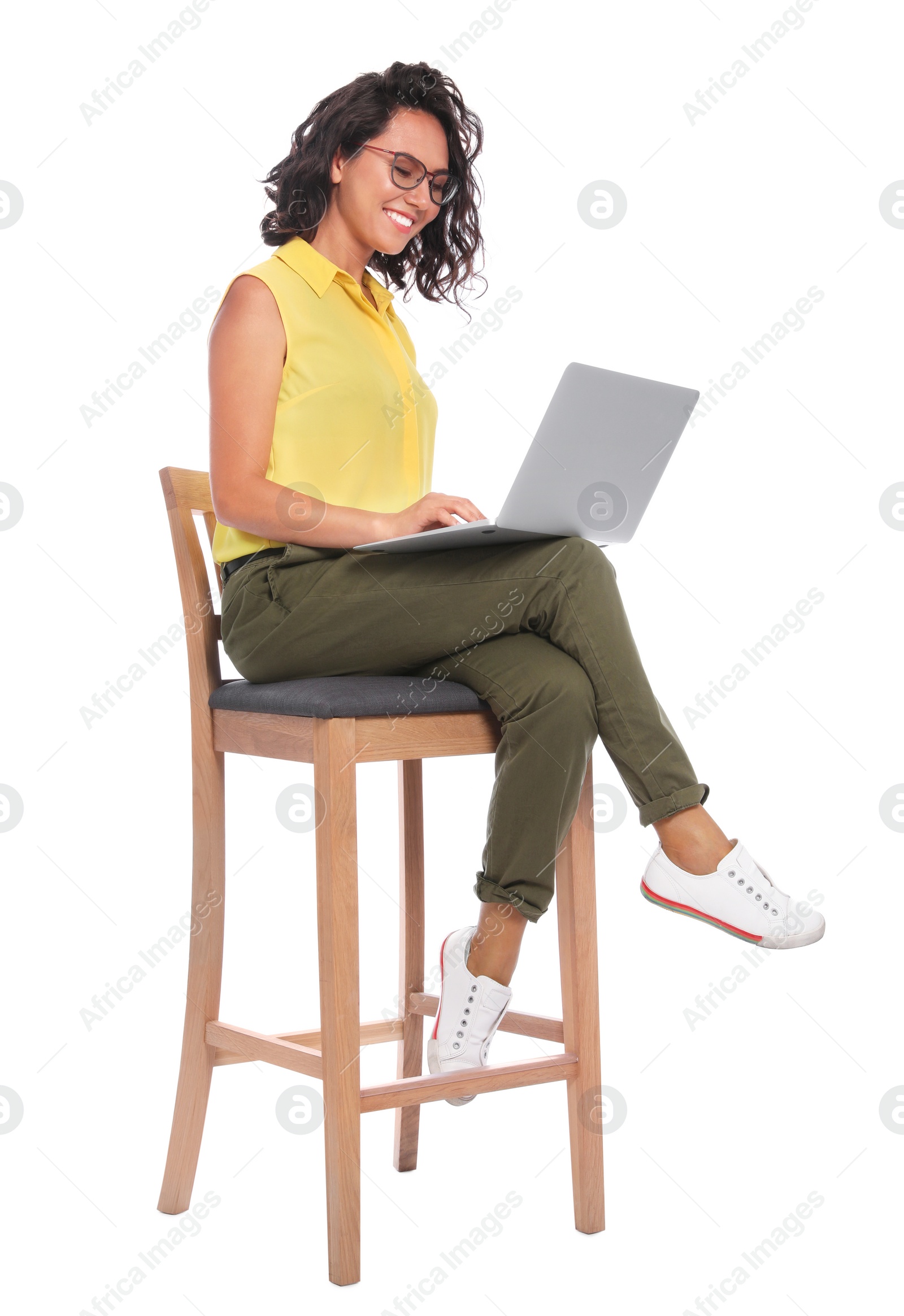 Photo of Happy young woman sitting on chair and working with laptop on white background