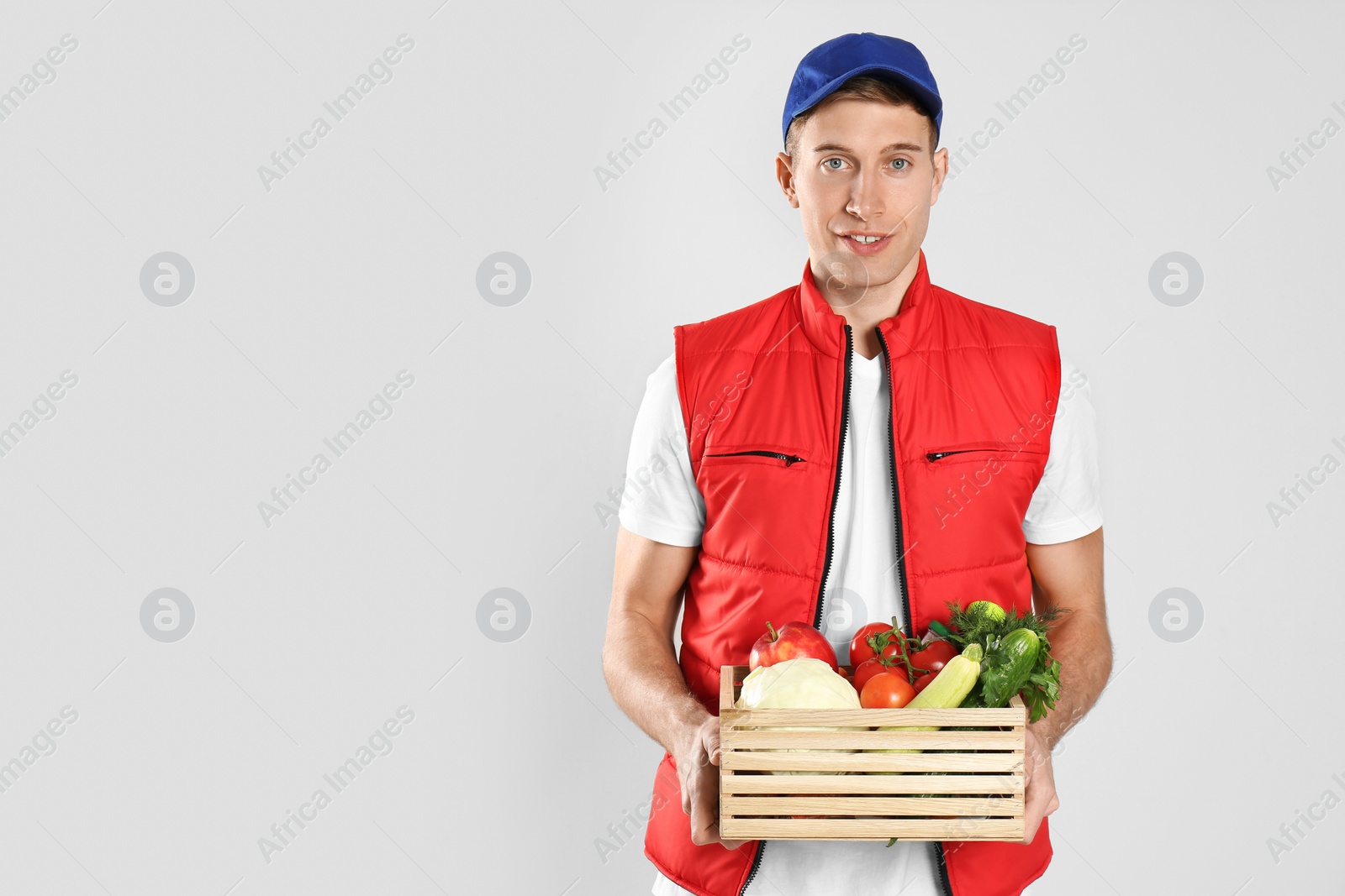 Photo of Courier with fresh products on light background, space for text. Food delivery service