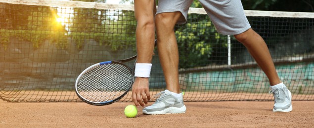 Image of Sportsman playing tennis at court on sunny day, closeup. Banner design