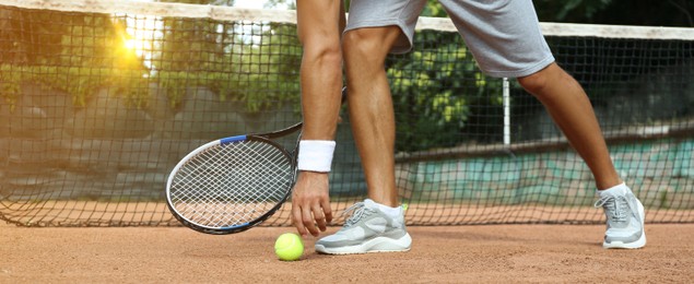 Sportsman playing tennis at court on sunny day, closeup. Banner design