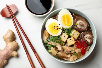 Delicious ramen served on white table, flat lay. Noodle soup