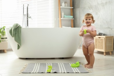 Photo of Cute little girl with toys in bathroom