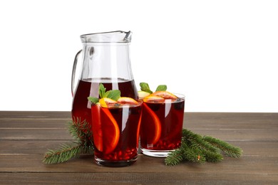 Photo of Aromatic Christmas Sangria drink and fir branches on wooden table against white background