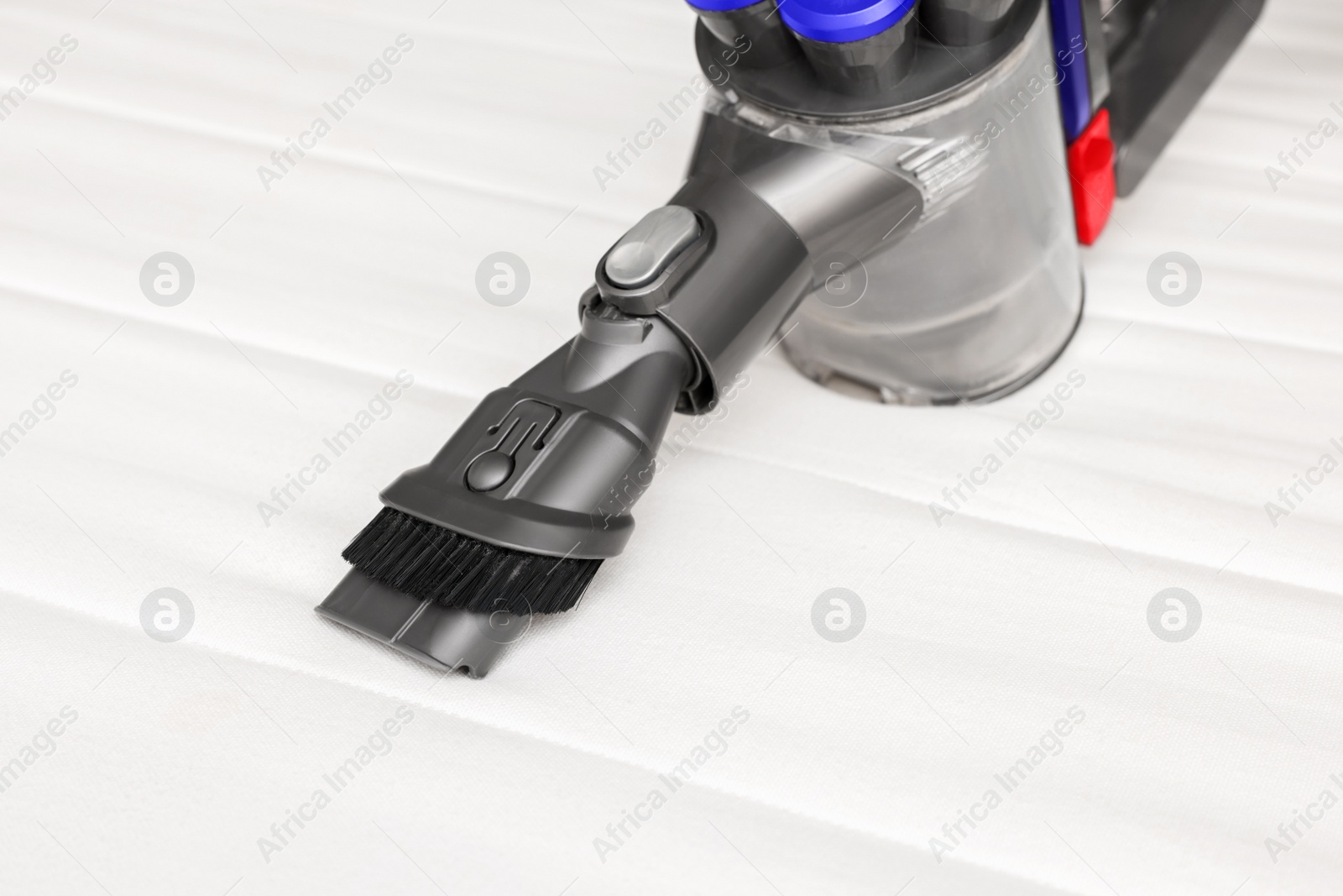 Photo of Modern vacuum cleaner on white mattress. Professional equipment