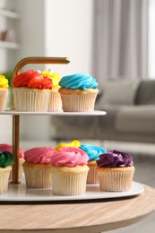 Photo of Delicious cupcakes with bright cream on wooden table indoors