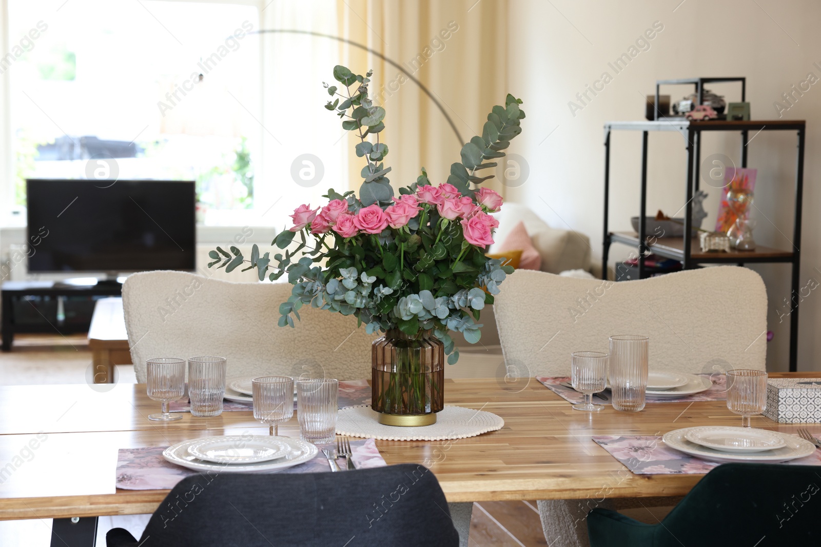 Photo of Beautiful table setting with bouquet in dining room. Roses and eucalyptus branches in vase