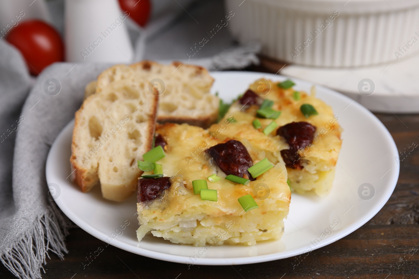 Photo of Tasty sausage casserole with green onion and bread on wooden table, closeup