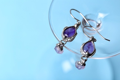 Photo of Beautiful pair of silver earrings with amethyst gemstones on light blue background