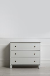 Photo of Stylish chest of drawers near white wall indoors, space for text