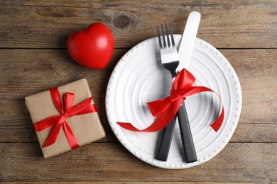 Photo of Beautiful place setting for romantic dinner on wooden table, flat lay. Valentine's day celebration
