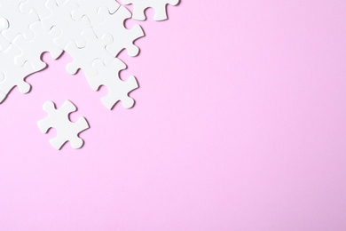 Photo of White puzzle on pink background, flat lay. Space for text