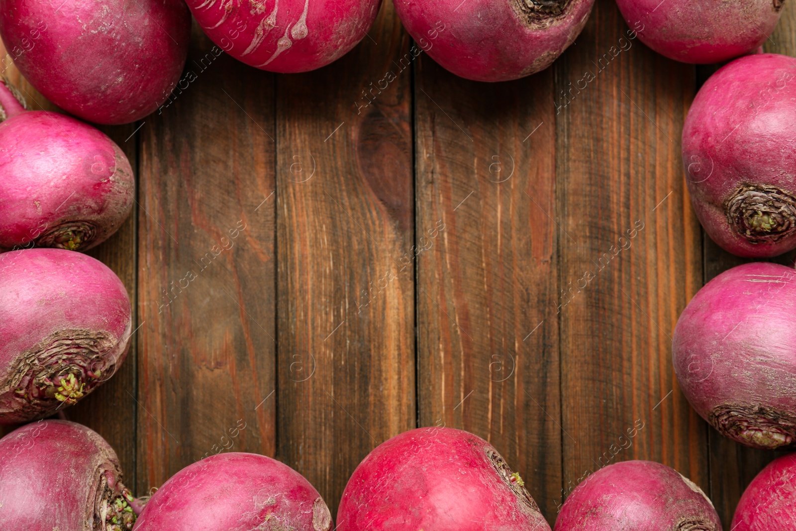 Photo of Frame made with red turnips on wooden table, flat lay. Space for text