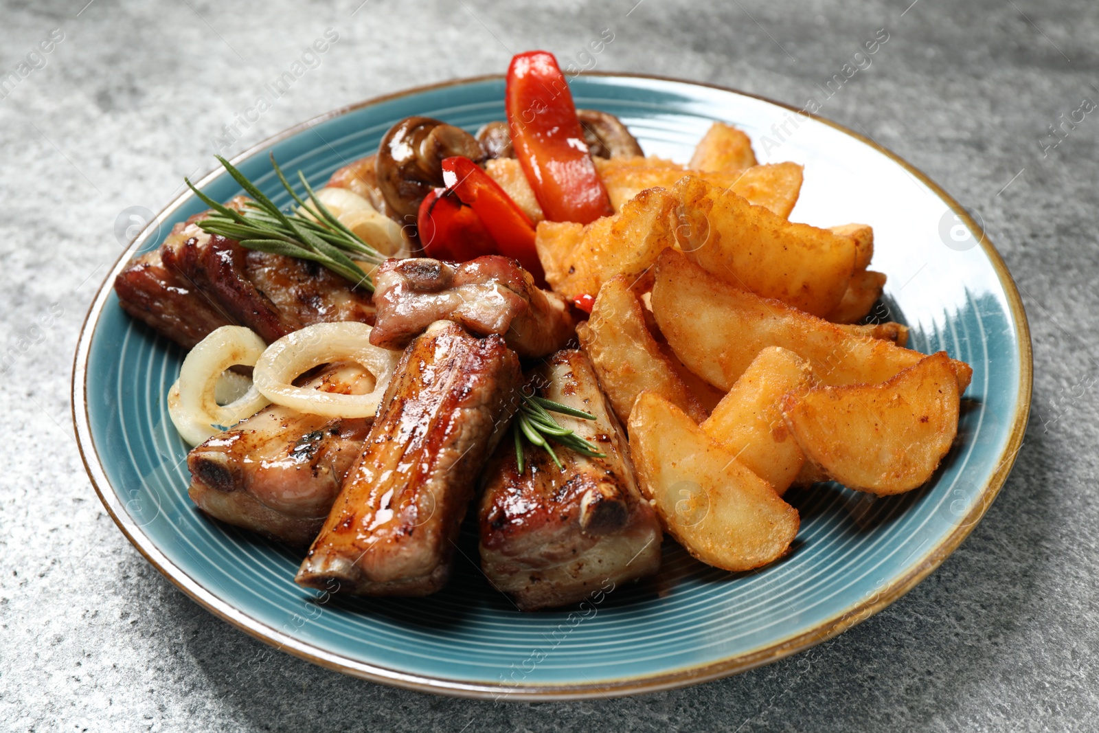 Photo of Delicious grilled ribs and garnish on grey table