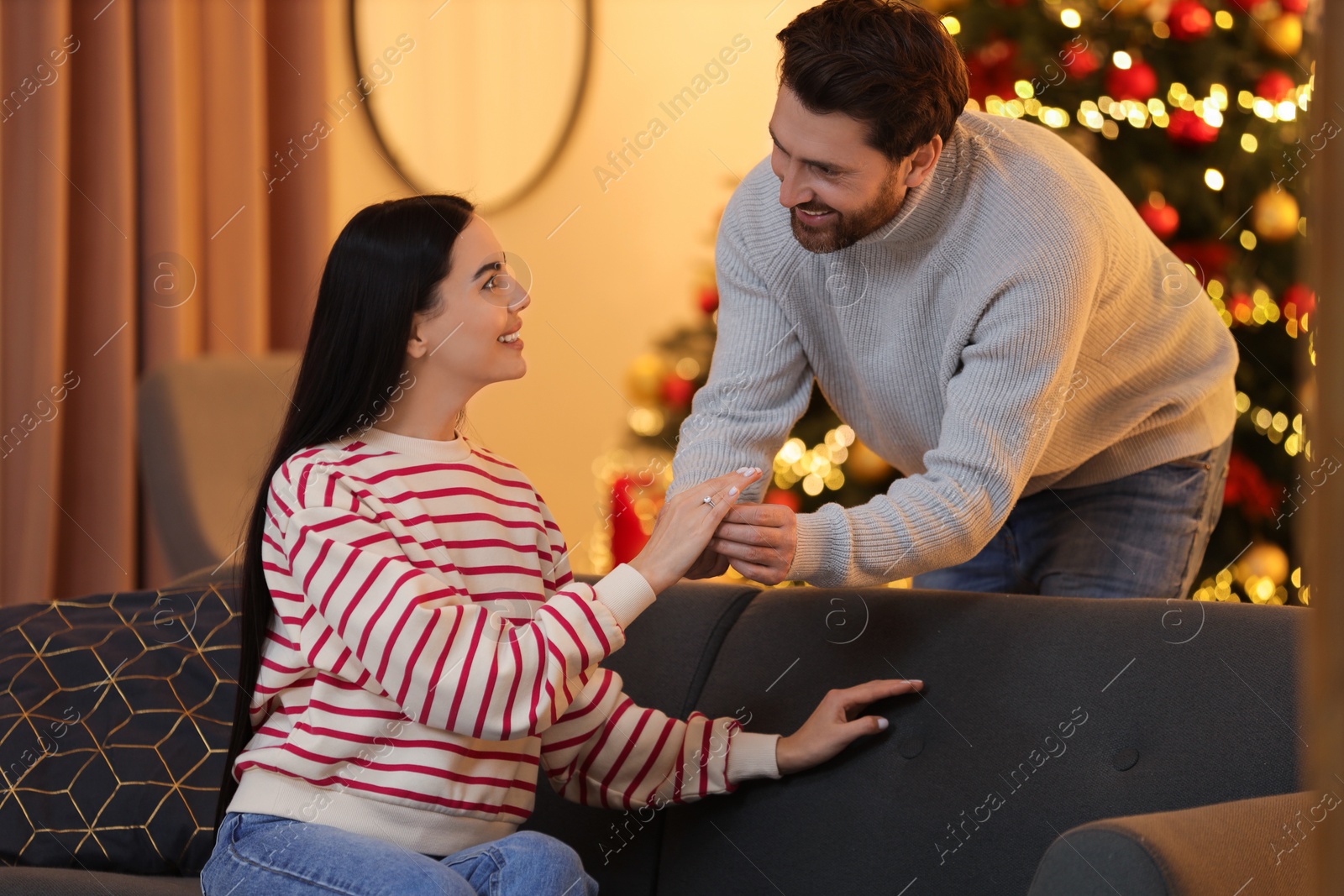 Photo of Making proposal. Man putting engagement ring on his girlfriend's finger at home on Christmas