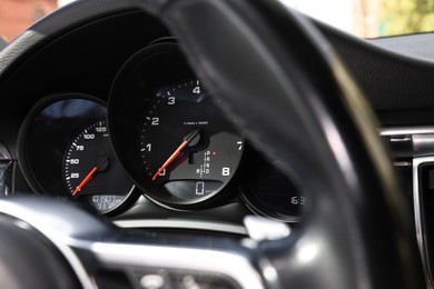 Photo of Steering wheel, speedometer and tachometer inside of modern car, closeup
