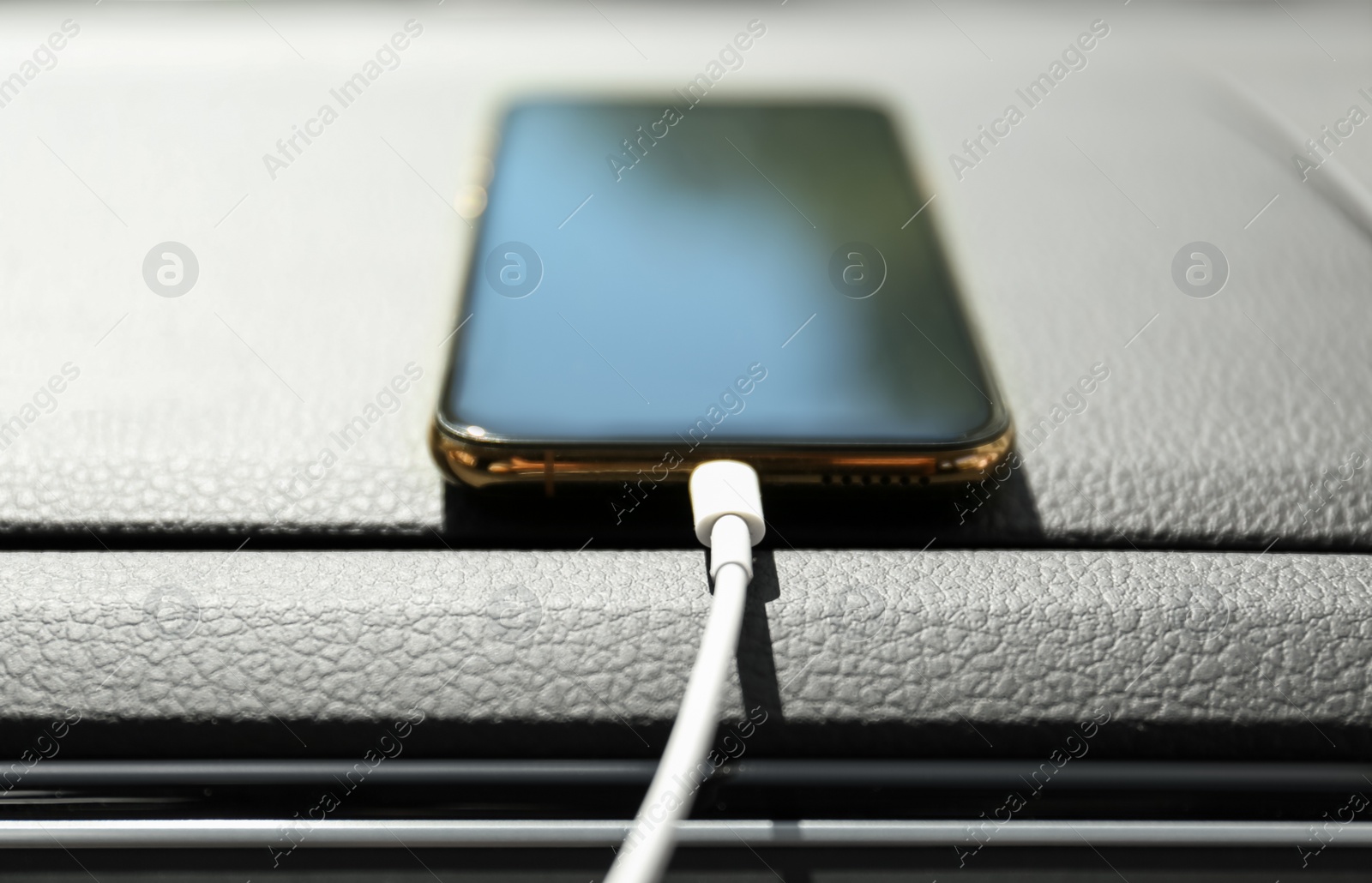 Photo of Smartphone with USB charging cable in modern car, closeup
