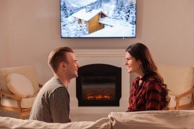 Photo of Happy lovely couple spending time together near fireplace at home