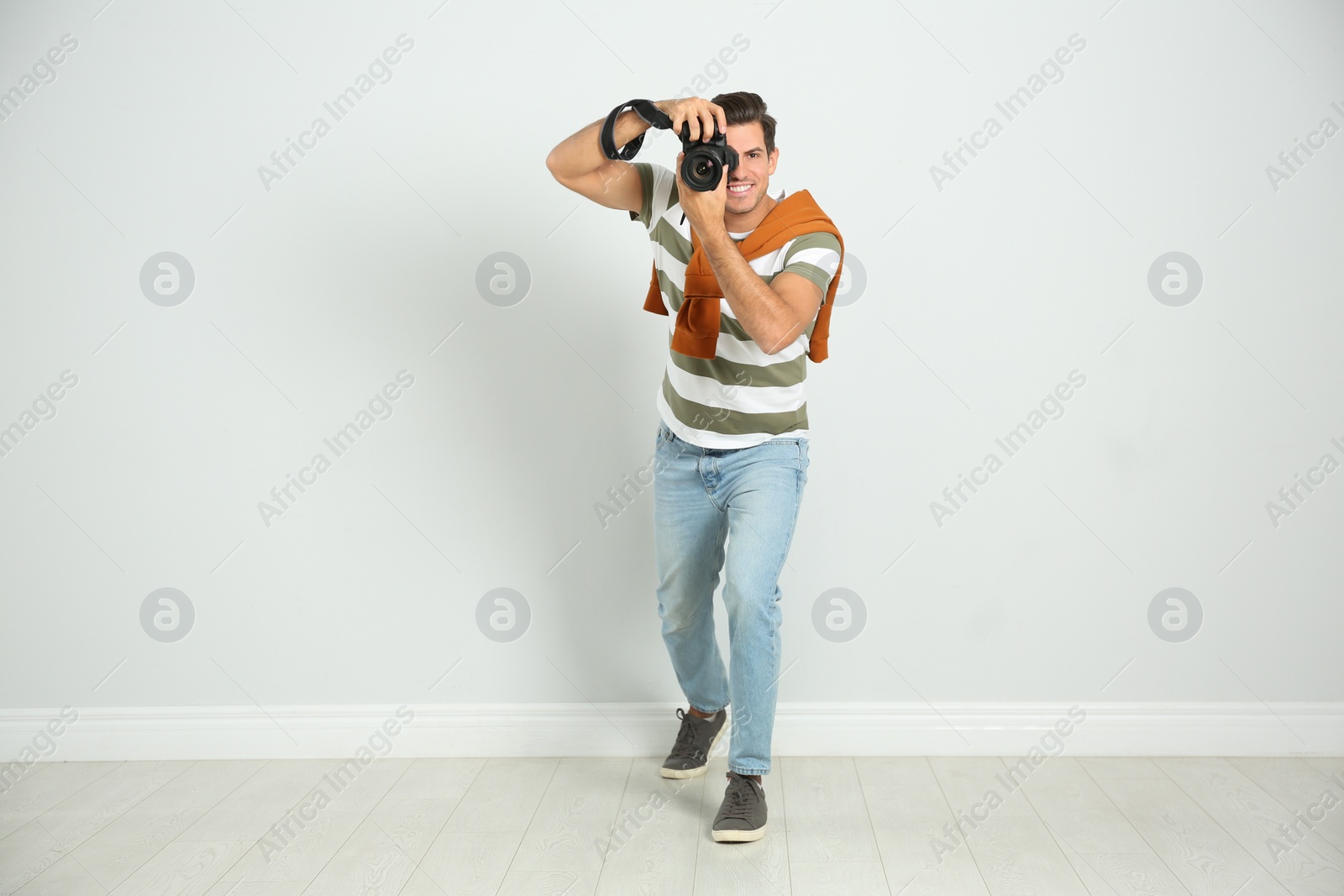 Photo of Professional photographer working near white wall in studio