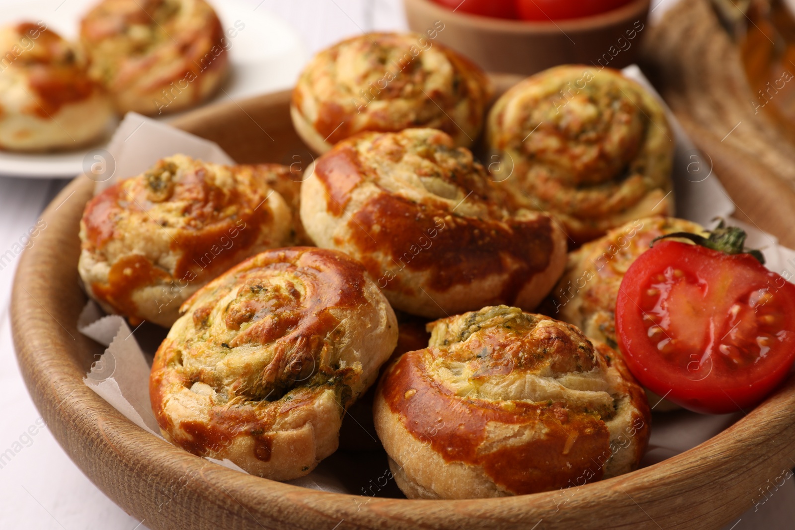 Photo of Fresh delicious puff pastry with tasty filling and tomato in wooden bowl, closeup