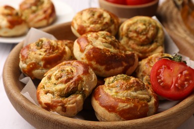 Photo of Fresh delicious puff pastry with tasty filling and tomato in wooden bowl, closeup